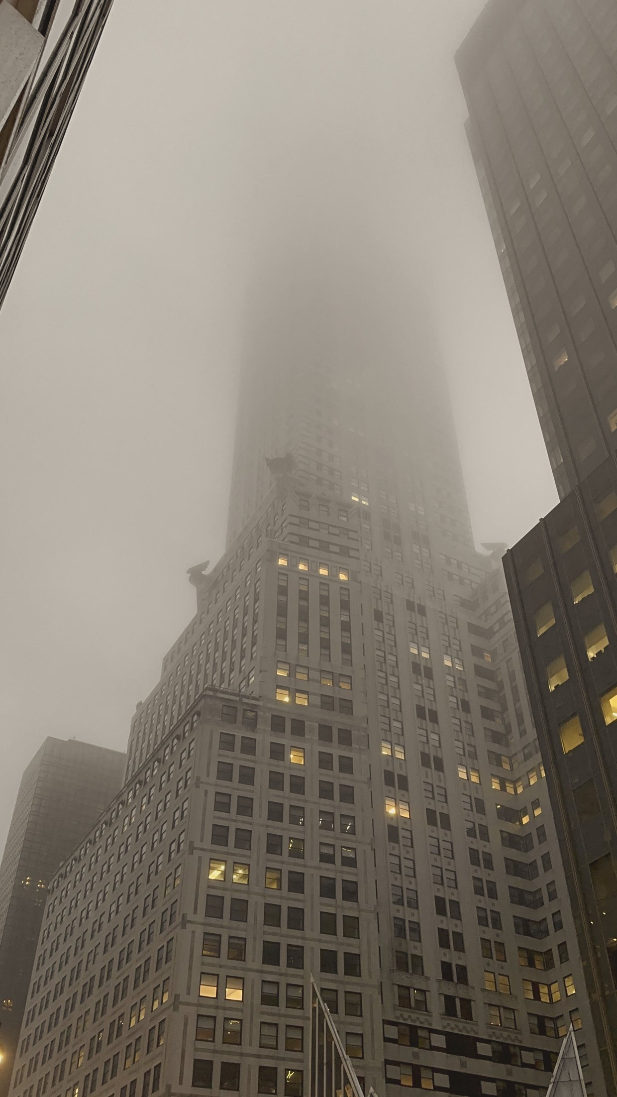 A Midtown Manhattan tower dissolving into fog, its lit windows showing through
